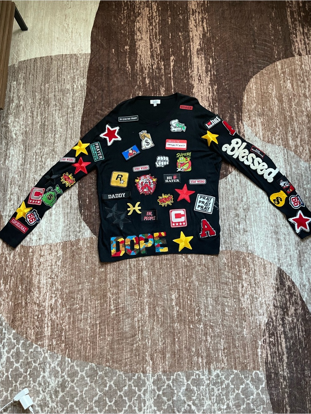 Black long sleeve sweater with colorful patches all over the front